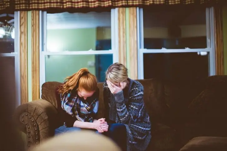 Two people comforting each other, upset by family separation.