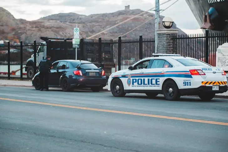 Is it illegal to drive with headphones - Policeman standing near personal car on road.